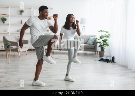 Junge schwarze Paar tun hohe Knie-Übung Stockfoto