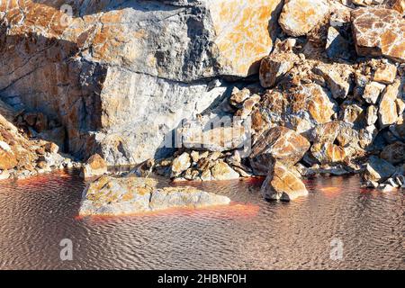 Detail der Tagebaugrube Peña del Hierro mit dem roten Wasser aufgrund der Kupfer- und Eisenkonzentration. Tiefaushub von Pyrit und Gewinnung von Mineralien Stockfoto