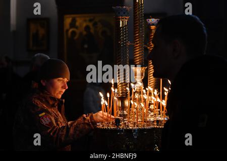 Swjatohirsk, Ukraine. 19th Dez 2021. Eine ukrainische Militärangehörende sah, wie sie in der Mariä Himmelfahrt-Kathedrale eine brennende Kerze aufsetzte.die Heilige Himmelfahrt Sviatohirsk Lavra ist ein wichtiges geistliches Zentrum der Ostukraine. Das orthodoxe Kloster befindet sich am rechten hohen Kreideufer des Flusses Siverskyi Donez (auf den sogenannten Heiligen Bergen) in der Stadt Swjatohirsk im Norden der Region Donezk. Kredit: SOPA Images Limited/Alamy Live Nachrichten Stockfoto