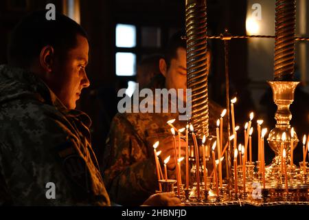 Swjatohirsk, Ukraine. 19th Dez 2021. Ukrainische Soldaten sahen brennende Kerzen in der Mariä-Himmelfahrt-Kathedrale platzieren.die Heilige Mariä-Himmelfahrt Swjatohirsk Lavra ist ein wichtiges geistliches Zentrum der Ostukraine. Das orthodoxe Kloster befindet sich am rechten hohen Kreideufer des Flusses Siverskyi Donez (auf den sogenannten Heiligen Bergen) in der Stadt Swjatohirsk im Norden der Region Donezk. Kredit: SOPA Images Limited/Alamy Live Nachrichten Stockfoto