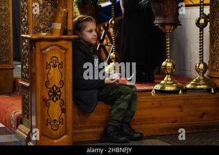 Swjatohirsk, Ukraine. 19th Dez 2021. Ein Kind, das während des Gottesdienstes in der Mariä Himmelfahrt-Kathedrale neben der Ikone sitzt.die Heilige Himmelfahrt Sviatohirsk Lavra ist ein wichtiges geistliches Zentrum der Ostukraine. Das orthodoxe Kloster befindet sich am rechten hohen Kreideufer des Flusses Siverskyi Donez (auf den sogenannten Heiligen Bergen) in der Stadt Swjatohirsk im Norden der Region Donezk. Kredit: SOPA Images Limited/Alamy Live Nachrichten Stockfoto