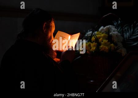 Swjatohirsk, Donezk, Ukraine. 27th. November 2021. Ein Mönch sah in der Mariä-Himmelfahrt-Kathedrale beten, während er eine brennende Kerze und ein Gebetsbuch hielt.die Heilige Himmelfahrt Sviatohirsk Lavra ist ein wichtiges spirituelles Zentrum der Ostukraine. Das orthodoxe Kloster befindet sich am rechten hohen Kreideufer des Flusses Siverskyi Donez (auf den sogenannten Heiligen Bergen) in der Stadt Swjatohirsk im Norden der Region Donezk. (Bild: © Andriy Andriyenko/SOPA Images via ZUMA Press Wire) Stockfoto