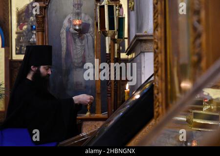 Swjatohirsk, Ukraine. 19th Dez 2021. Ein Mönch sah während des Gottesdienstes in der Mariä Himmelfahrt-Kathedrale eine Kerze in der Nähe der Ikonen anzünden.die Heilige Himmelfahrt Sviatohirsk Lavra ist ein wichtiges spirituelles Zentrum der Ostukraine. Das orthodoxe Kloster befindet sich am rechten hohen Kreideufer des Flusses Siverskyi Donez (auf den sogenannten Heiligen Bergen) in der Stadt Swjatohirsk im Norden der Region Donezk. (Foto von Andriy Andriyenko/SOPA Images/Sipa USA) Quelle: SIPA USA/Alamy Live News Stockfoto