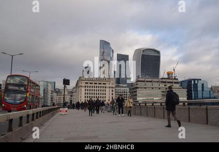 Die Menschen laufen auf der London Bridge an der Skyline der City of London vorbei. London, Großbritannien 14. Dezember 2021. Stockfoto