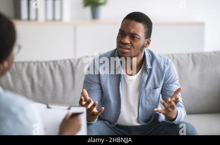 Psychologe hilft depressiven jungen schwarzen Mann, Beratung zu männlichen Patienten im Büro Stockfoto