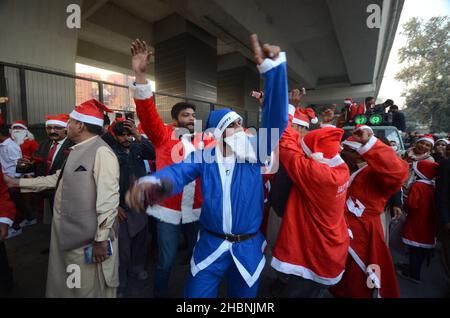 Peshawar, Pakistan. 20th Dez 2021. Mitglieder der christlichen Minderheit Pakistans, die als Weihnachtsmänner gekleidet ist, nehmen an einer vorweihnachtlichen Kundgebung auf einer Straße in Peshawar Teil. Pakistan ist ein muslimisches Land mit sunnitischer Mehrheit und vier Millionen Christen bei einer Gesamtbevölkerung von etwa 200 Millionen Menschen. (Foto: Hussain Ali/Pacific Press) Quelle: Pacific Press Media Production Corp./Alamy Live News Stockfoto