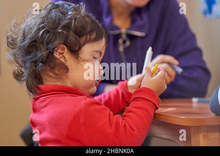 Das Kind versucht mit einem Bleistift zu zeichnen Stockfoto