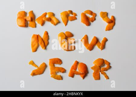Defokussieren Happy New Year Wort durch orange trockene Schale auf einem isolierten weißen Hintergrund angezeigt. Dekoration für Silvester, Konzept. Grußkarte. Text Stockfoto