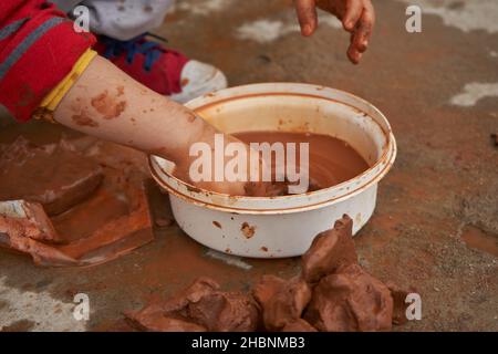 Kinderhände Formen Ton in einer Schüssel. Stockfoto