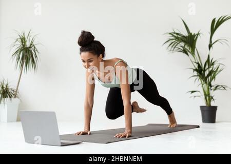 Online-Tutorials. Sportliche Frau trainiert zu Hause vor dem Laptop Fitness Stockfoto