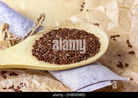 Rohe, trockene Leinsamen in einem Holzlöffel auf hellem Hintergrund anbraten. Stockfoto