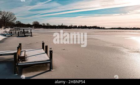 Am Ufer des Lake Winneconne im ländlichen Wisconsin liegen eine Reihe von Docks. Die Sonne ist hell und schmilzt den Schnee kurz nach einem Neuschnee fallen. Stockfoto