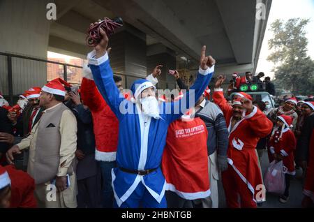 Peshawar, Pakistan. 20th Dez 2021. (12/20/2021) Mitglieder der christlichen Minderheit Pakistans, die als Weihnachtsmänner gekleidet ist, nehmen an einer vorweihnachtlichen Kundgebung auf einer Straße in Peshawar Teil. Pakistan ist ein muslimisches Land mit sunnitischer Mehrheit und vier Millionen Christen bei einer Gesamtbevölkerung von etwa 200 Millionen Menschen. (Foto: Hussain Ali/Pacific Press/Sipa USA) Quelle: SIPA USA/Alamy Live News Stockfoto