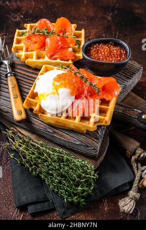 Waffle Sandwich mit Frischkäse, geräuchertem Lachs, Ei und rotem Kaviar. Dunkler Hintergrund. Draufsicht Stockfoto