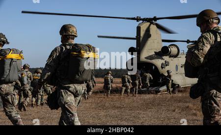 Fallschirmjäger der US-Armee besteigen einen CH-47 Chinook Hubschrauber, der der Kampffliegerbrigade 82nd während einer Flugübung in der Fallzone Sizilien, Fort Bragg, North Carolina, zugewiesen wurde, 15. Dezember 2021. Das U.S. Army Reserve Civil Affairs and Psychological Operations Command (Airborne) und die 824th Quartermaster Company haben sich mit Soldaten der 82nd Airborne Division zusammengeschlossen, um eine nicht-taktische Luftoperation mit verbündeten Sprungmeistern durchzuführen, um die Kompetenz zu erhalten und ausländische Sprungflügel zu verdienen, 13.-15. Dezember 2021. (USA Armee-Foto von SPC. Cody Rich) Stockfoto