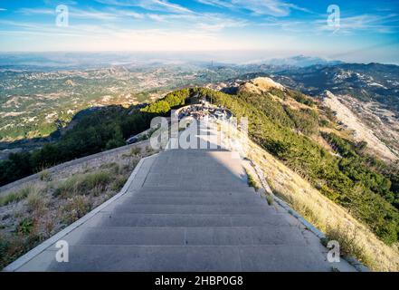 Lovcen, Montenegro-September 14 2019: Bei Sonnenuntergang steigen Besucher und Wanderer vom Parkplatz hinauf, in Richtung eines langen Tunnels, der durch den Berg führt, und Stufen Stockfoto