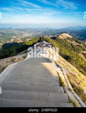 Lovcen, Montenegro-September 14 2019: Bei Sonnenuntergang steigen Besucher und Wanderer vom Parkplatz hinauf, in Richtung eines langen Tunnels, der durch den Berg führt, und Stufen Stockfoto