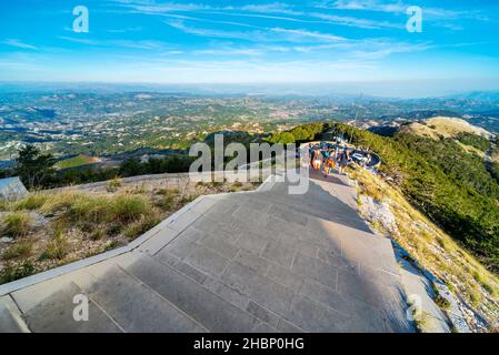 Lovcen, Montenegro-September 14 2019: Bei Sonnenuntergang steigen Besucher und Wanderer vom Parkplatz hinauf, in Richtung eines langen Tunnels, der durch den Berg führt, und Stufen Stockfoto