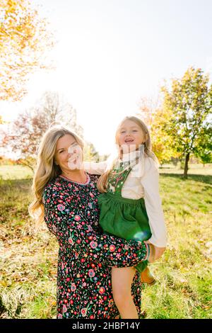 Porträt einer Mutter, die ihre Tochter im Schulalter hält Stockfoto