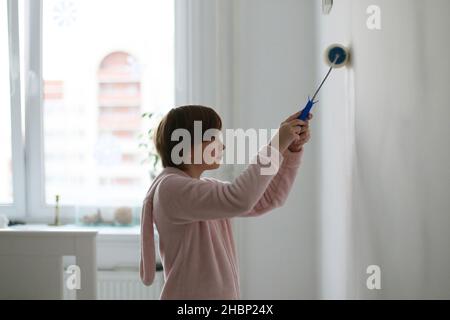 Das Kind malt die Wand im Zimmer. Stockfoto