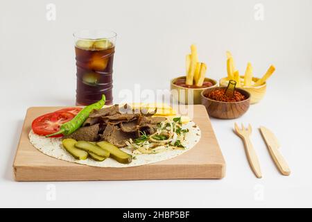 Traditioneller türkischer Kebab, Döner-Menü mit kaltem Getränk und gebratenen Kartoffeln auf dem hölzernen Essensservice. Weißer Hintergrund. Stockfoto