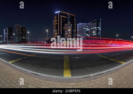 DUBAI, VEREINIGTE ARABISCHE EMIRATE - 11. Nov 2021: Eine Nachtaufnahme von Gebäuden entlang der Autobahn und Ampelwegen, Dubai, VAE Stockfoto