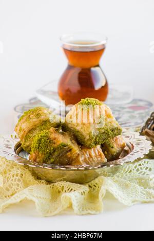 Traditionelles türkisches Gebäck Dessert Dry Baklava auf Weiß mit Vintage-Schale, handgefertigtem Spitzentuch und Tee. Stockfoto