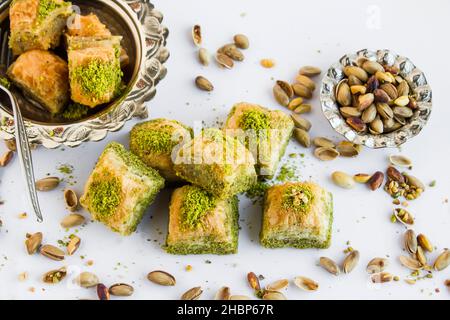 Traditionelles türkisches Konditorei-Dessert, trockene Baklava, in einer Vintage-Kupferschale auf Weiß mit Pistazien-Nüssen, oben Stockfoto