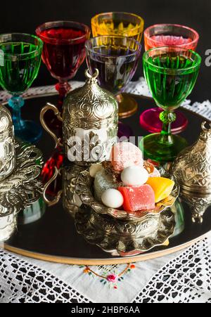 Eine alte Tradition; Likör und traditioneller türkischer Kaffee auf dem runden Spiegeltablett mit türkischen Köstlichkeiten und Süßigkeiten. Stockfoto