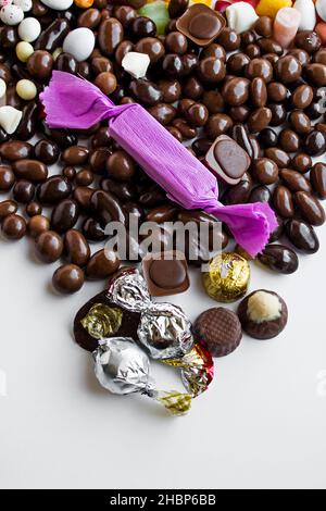 Bunte Bonbons und dunkle Schokoladenkugeln auf weißem Hintergrund mit Kopierfläche. Stockfoto