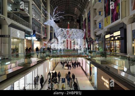 Das Eaton Centre in Toronto ist ein mehrstufiger Einkaufszentrum mit hellen Weihnachtsdekorationen und Einkaufsküppern, die aufgrund der Pandemie Gesichtsmasken tragen Stockfoto