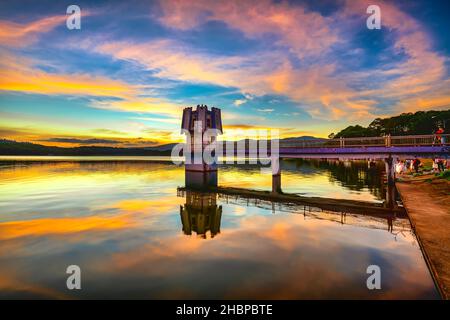 Die leuchtenden Farben des Sonnenuntergangs am Seeufer, wo sich der Wasserkraftdamm befindet, locken viele Besucher an Wochenenden zum Entspannen an Stockfoto