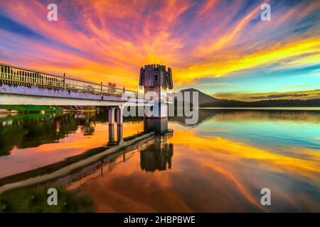 Die leuchtenden Farben des Sonnenuntergangs am Seeufer, wo sich der Wasserkraftdamm befindet, locken viele Besucher an Wochenenden zum Entspannen an Stockfoto