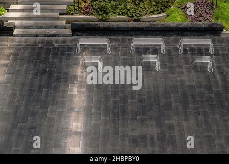 Perspektivische Weißmetall-Bänke im Freien im offenen leeren Bereich des Parks mit Kopierfläche. Sitz- und Relaxbereich. Selektiver Fokus. Stockfoto