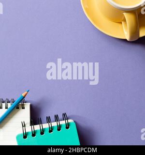 Notizblock und Tasse auf violettem Hintergrund. Flach liegend, Draufsicht, Kopierraum Stockfoto