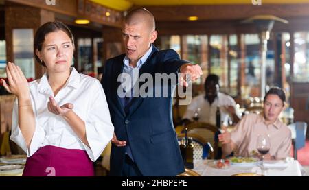 Der Besitzer des Restaurants schreit den schuldig Kellner an Stockfoto