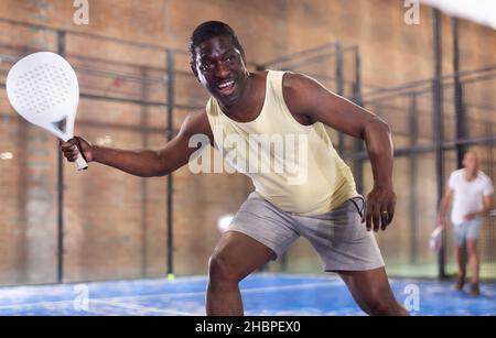 Ausdrucksstarker afroamerikaner, der auf einem geschlossenen Platz Paddle-Ball spielt Stockfoto