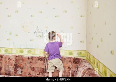 Boy zeichnet an den Wänden. Kind hat Spaß und Flecken an der Wand Stockfoto