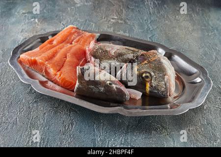 Frisches Lachsfilet und Kopf frischer Barsch bereit zum Kochen auf Tablett Stockfoto
