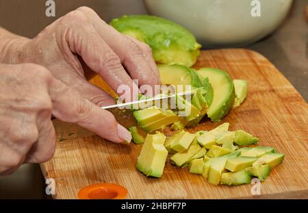 Cook schneidet reife Avocado für die Salatherstellung in Scheiben Stockfoto