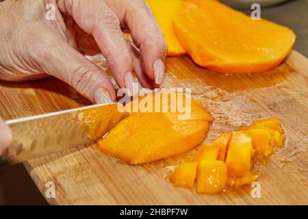 Cook schneidet saftige Mango in Scheiben, um Salat zuzubereiten Stockfoto