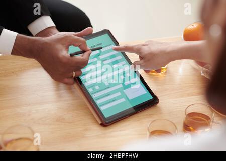 Nahaufnahme eines Agenten, der dem Kunden erklärt, wie er das Formular für Krankenversicherungen auf einem digitalen Tablet ausfüllen kann Stockfoto