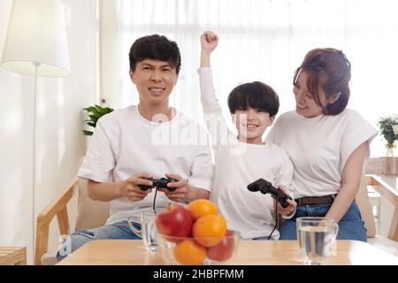 Aufgeregt preteen Junge feiern schlug Vater im Videospiel Stockfoto
