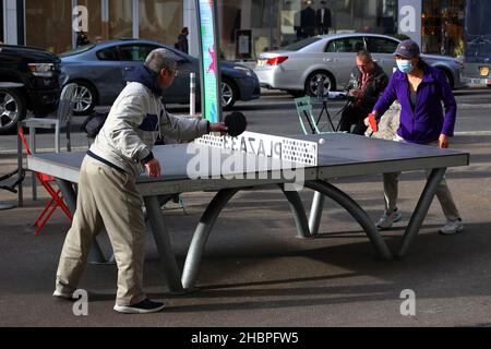 Zwei Personen asiatischer Herkunft spielen Tischtennis auf einem Cornilleau Park Outdoor-Tisch im öffentlichen Raum Plaza 33 in der Nähe des Herald Square in New York City Stockfoto