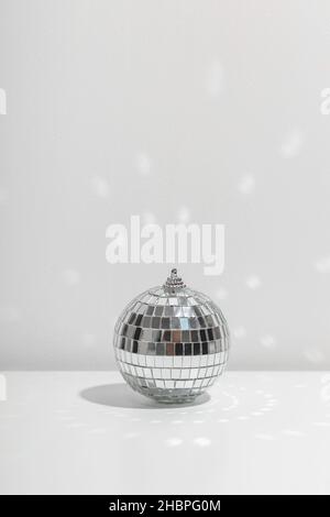 Die silberne Discokugel reflektiert Sonnenlicht auf silbernem Hintergrund. Stockfoto