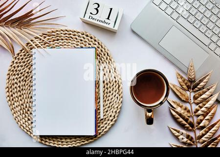 Notizblock mit Laptop, Kalender mit 31st. Dezember, goldene Metalldekorationen. Auflösung des neuen Jahres, Neuanfang und Zielverzeichnis. Gemütliche Wohnästhetik. Draufsicht. Speicherplatz kopieren. Stockfoto