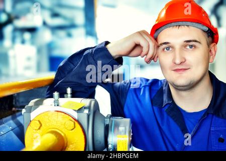 Portrait des jungen Ingenieurs im Helm in der Arbeitswelt in der Fabrik. Gasarbeiter blickt selbstbewusst direkt in die Kamera. Gasausrüstungsmonteur. Nahaufnahme des Mitarbeiters in Schutzkleidung im Heizraum. Heller Hintergrund. Stockfoto