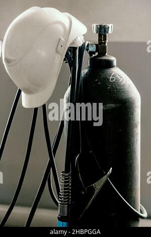 Der Konstruktionshelm wird auf dem Sauerstoffzylinder in der Schweißwerkstatt getragen. Industrie und Bauwesen. Hintergrund. Stockfoto