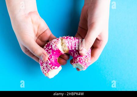 Hand hält halb gegessen süßen rosa Donut isoliert. Halb verzehrter Donut isoliert. Stockfoto