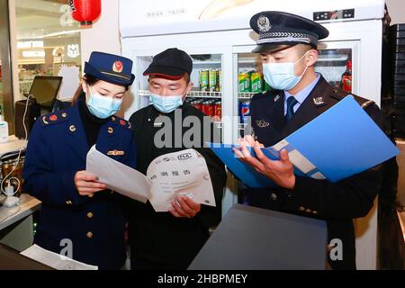 ZHOUSHAN, CHINA - 21. DEZEMBER 2021 - Polizeibeamte überprüfen den Bericht über Lebensmitteltests in der Kühlkette in der Stadt Zhoushan, Provinz Zhejiang, China, Stockfoto